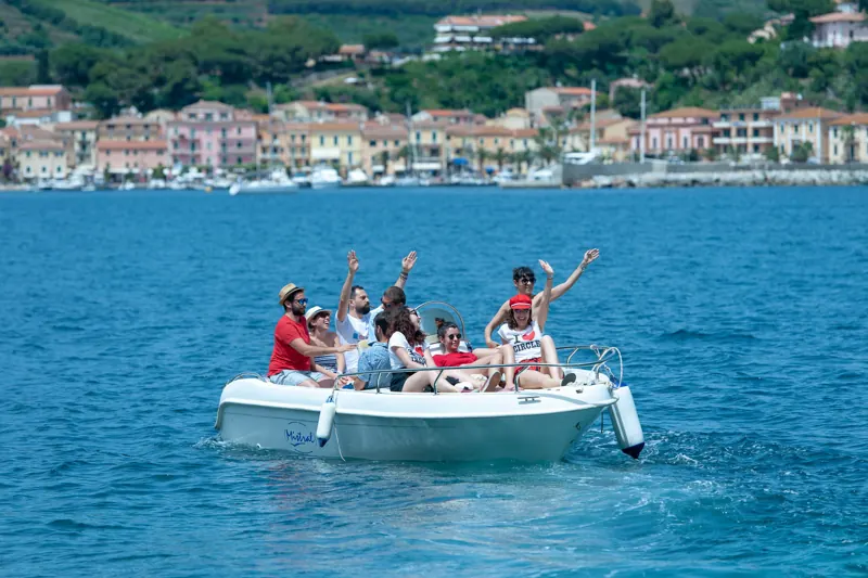 Una barca di ballerini in mare davanti al paese